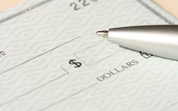 a pen sitting on top of a cheque paper by Money Knack courtesy of Unsplash.