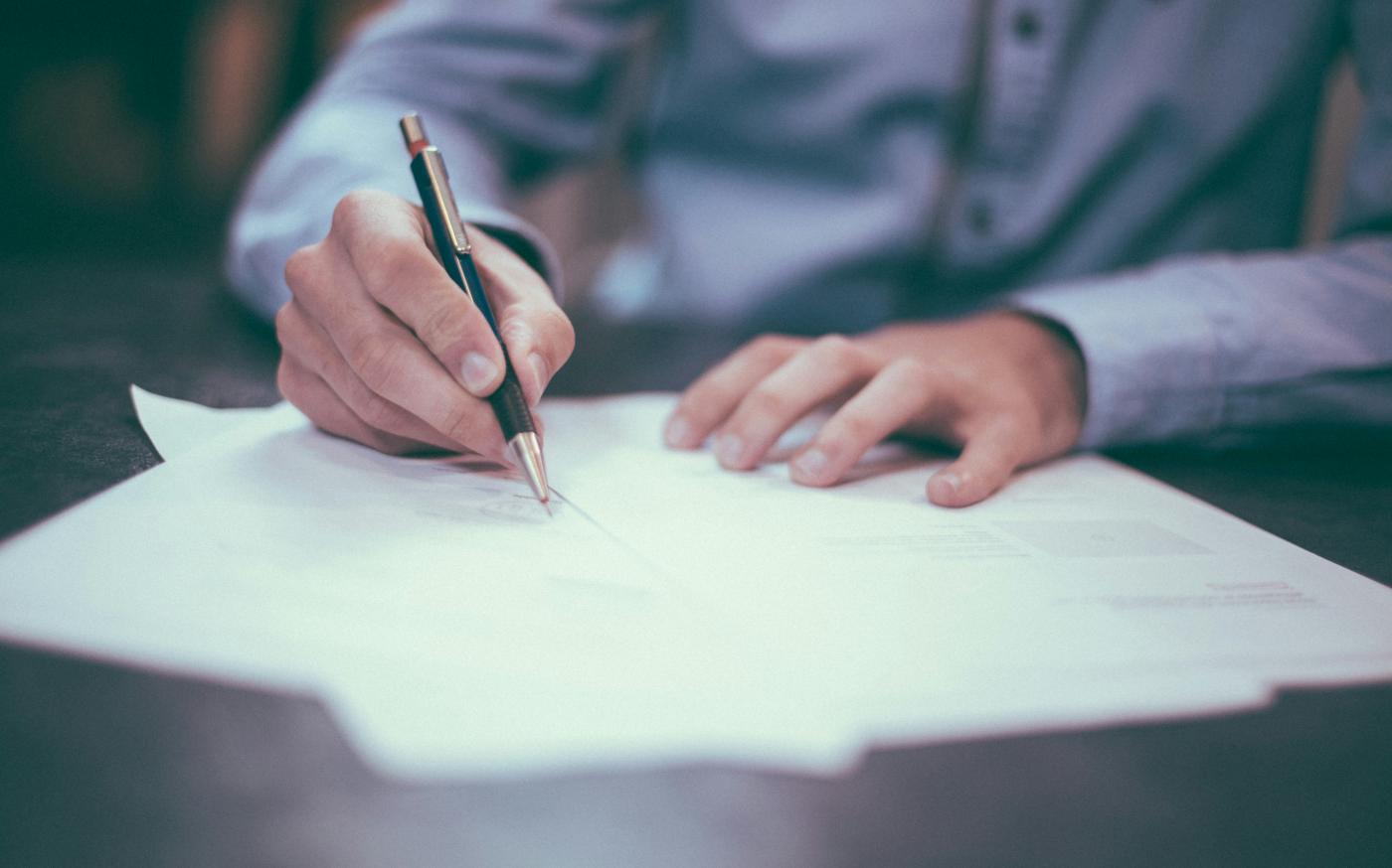 man writing on paper by Scott Graham courtesy of Unsplash.