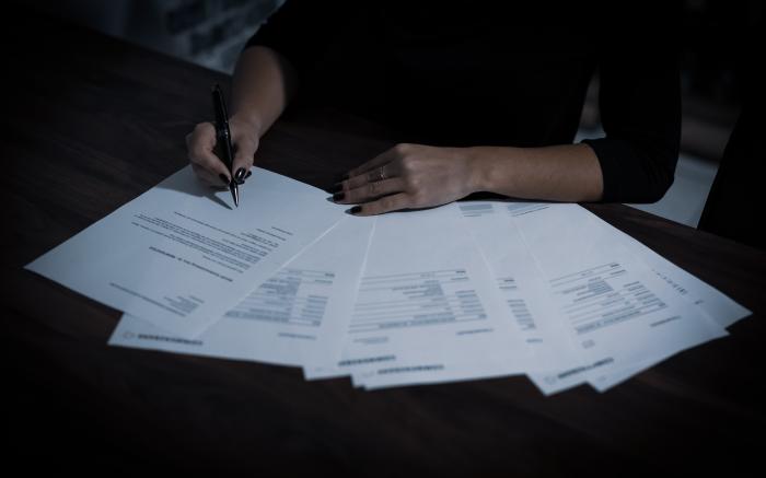 a woman sitting at a table with lots of papers by Dimitri Karastelev courtesy of Unsplash.
