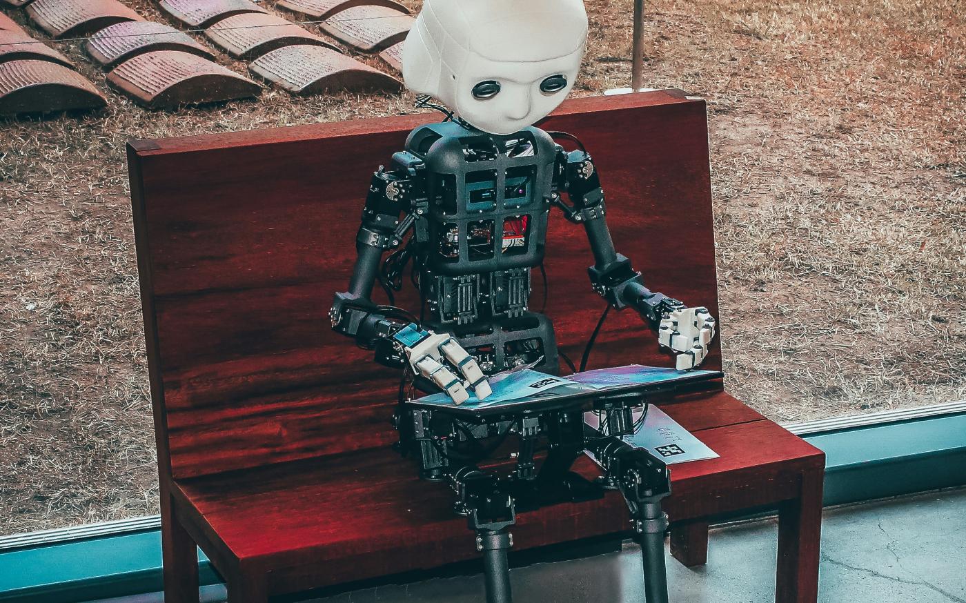 black and white robot toy on red wooden table by Andrea De Santis courtesy of Unsplash.