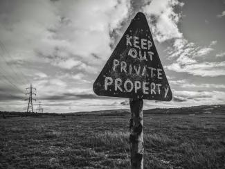 a black and white photo of a sign that says keep out private property by Charlie Hammond courtesy of Unsplash.