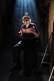man wearing black and beige striped polo shirt and black pants sitting on stool with lights by Ozan Safak courtesy of Unsplash.