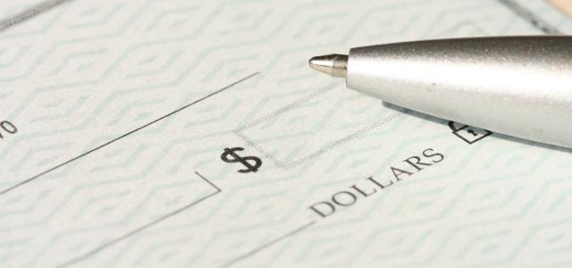 a pen sitting on top of a cheque paper by Money Knack courtesy of Unsplash.