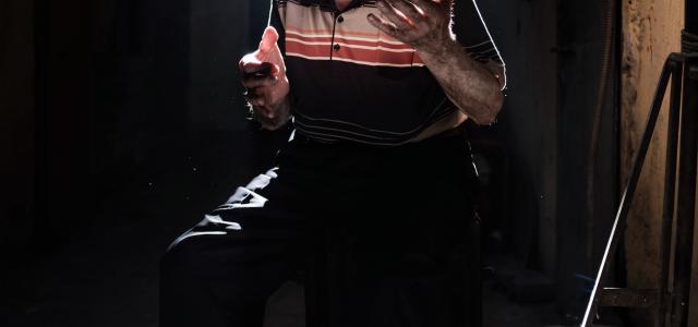 man wearing black and beige striped polo shirt and black pants sitting on stool with lights by Ozan Safak courtesy of Unsplash.